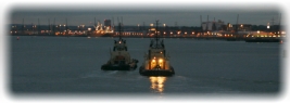 Sunset view of harbour with vessel and buoy lights.